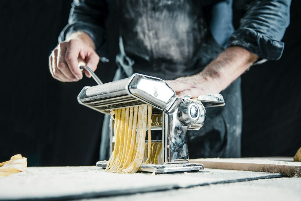 Hobby chef making fresh tagliatelle with pasta machine